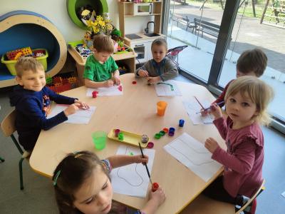 4 chłopców i 2 dziewczynki siedzą przy stoliku i malują farbami szablon skarpety