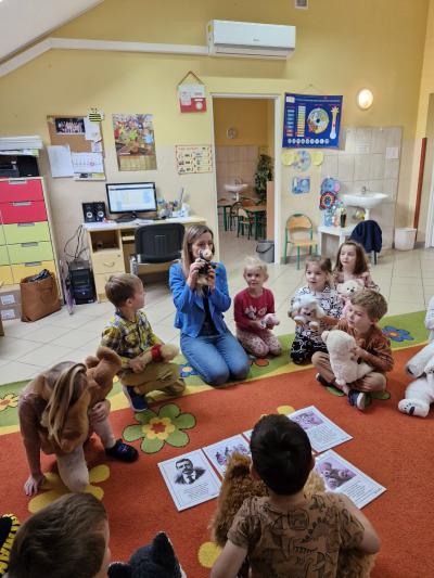 Pani trzyma misia , dzieci siedzą w kole na dywanie..jpg