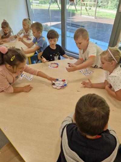 Dzieci siedzą przy stolikach i malują palcami.jpg