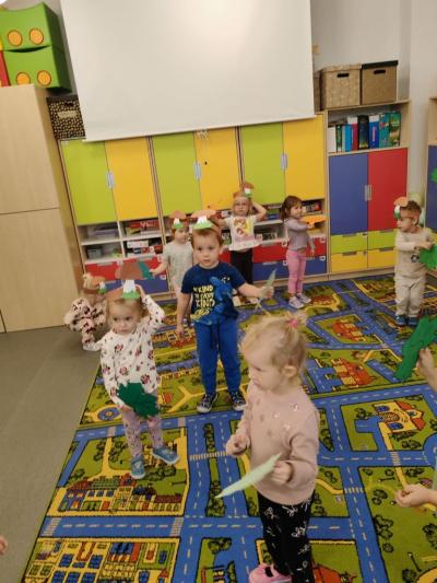 Dzieci z grupy krasnale tańczą na dywanie machając listeczkami..jpg