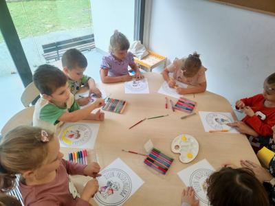 Trzy dziewczynki i trzech  chłopców przy stoliku kolorują medal z okazji Dnia Przedszkolaka..jpg