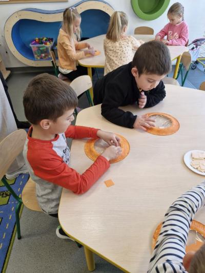 Chłopcy siedzą przy stoliku i wykonują pracę plastyczną.jpg