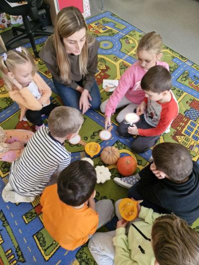 Dzieci siedzą na dywanie i biorą udział w zajęciach.jpg