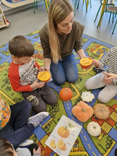 Dzieci siedzą na dywanie i oglądają wnętrze dyni.jpg