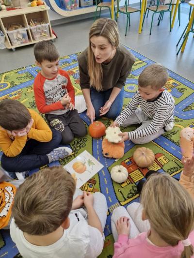 Dzieci siedzą na dywanie i słuchają ciekawostek o dyni.jpg