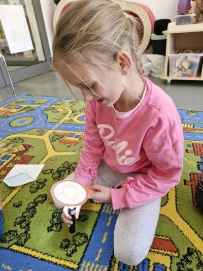 Dziewczynka ogląda produkty z dyni za pomocą latarki.jpg