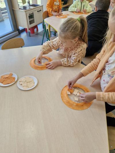 Dziewczynka siedzi przy stoliku i wykonuje pracę plastyczną.jpg