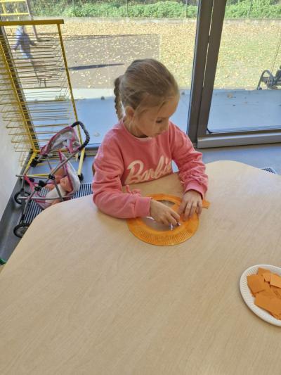 Dziewczynka siedzi przy stoliku i wykonuje pracę plastyczną (2).jpg