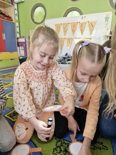 Dziewczynki oglądają produkty z dyni za pomocą latarki.jpg