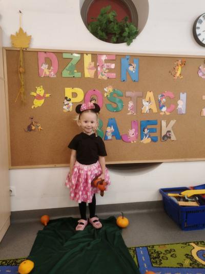 Dziewczynka na tle tablicy pozuje do zdjecia.jpg