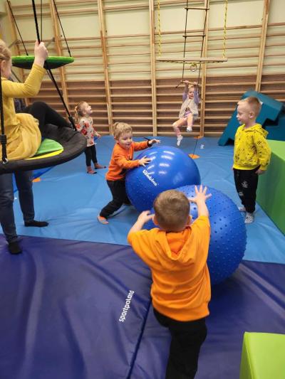 Dwóch chłopców toczy niebieskie duże piłki po sali ćwiczeń..JPG