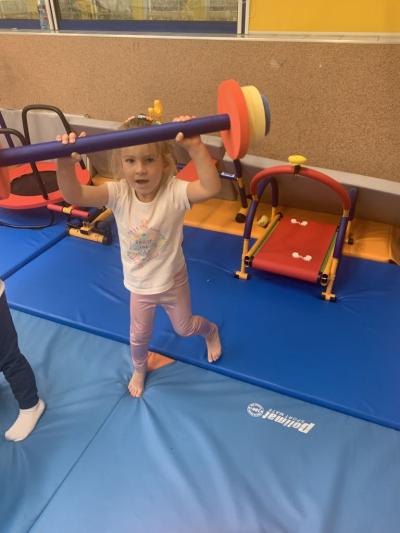 Dziewczynka podnosi mini sztangę w sali ćwiczeń..jpg