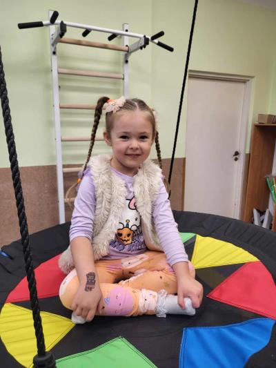 Dziewczynka siedzi na huśtawce typu bocianie gniazdo w sali ćwiczeń..JPG