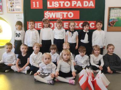 Zdjęcie grupowe dzieci z grupy Sówki. W tle tablica z dekoracją..jpg