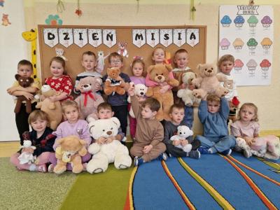 Dzieci z pluszakami stoją przy tablicy.jpg