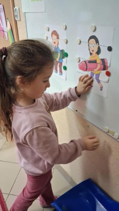 4. Dziewczynka przyczepia fragment obrazka do tablicy magnetycznej..JPG