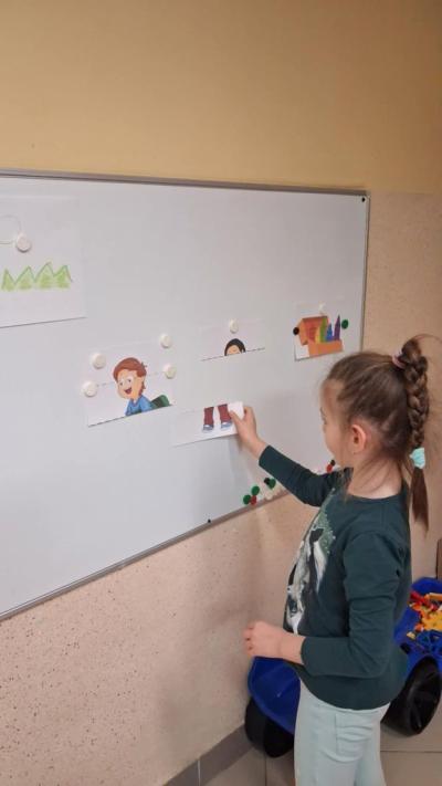 5. Dziewczynka przyczepia fragment obrazka do tablicy magnetycznej..JPG