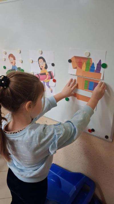 6. Dziewczynka przyczepia fragment obrazka do tablicy magnetycznej.JPG