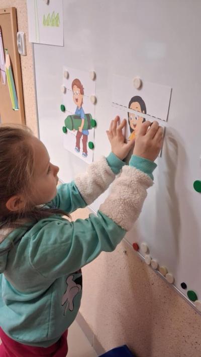 7. Dziewczynka przyczepia fragment obrazka do tablicy magnetycznej.JPG
