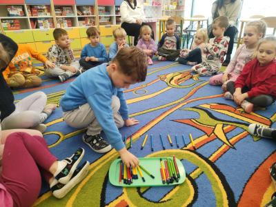 Chłopiec układa kredki na dywanie..jpg