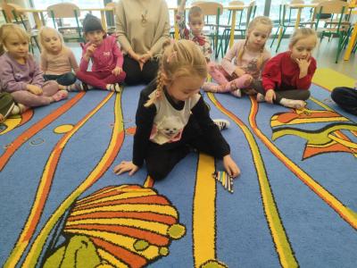 Dziewczynka układa na dywanie kredki..jpg