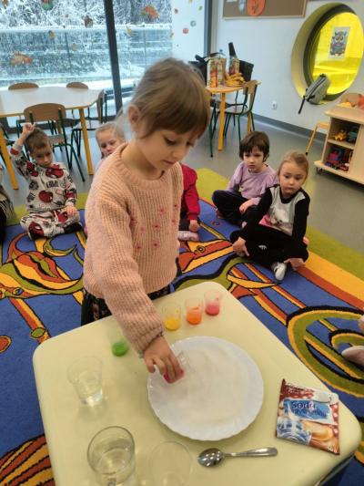 Dziewczynka wlewa czerwoną farbę na talerz..jpg