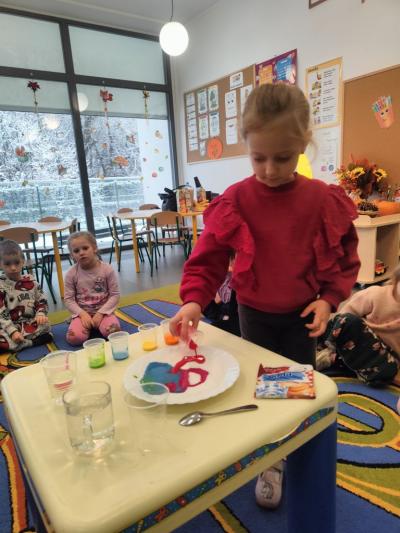 Dziewczynka wylewa różową farbkę na talerz..jpg