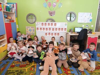 dzieci pozują do zdjęcia z misiami, na tablicy napis dzień pluszowego misia.jpg