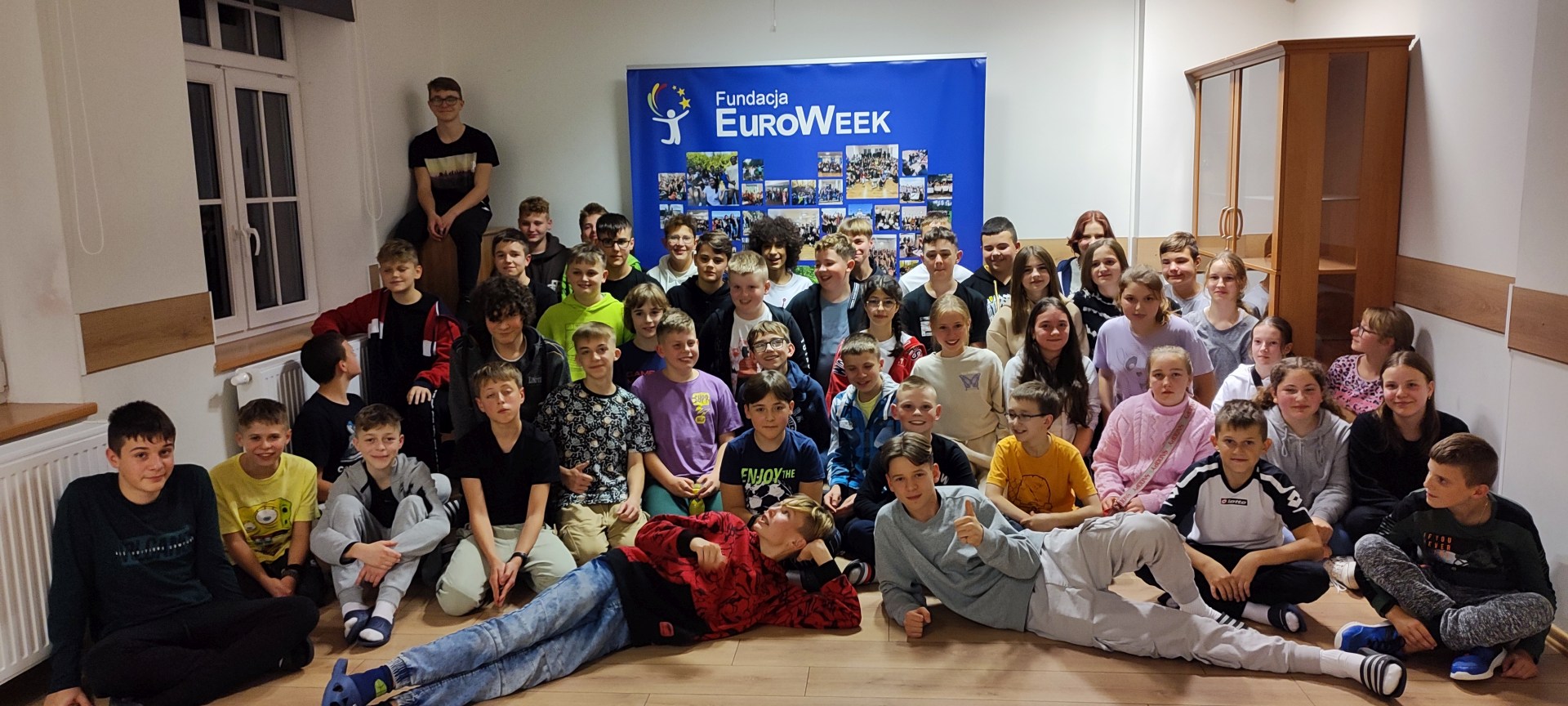 Grupowe zdjęcie wszystkich uczestników projektu na tle plakatu EuroWeek.