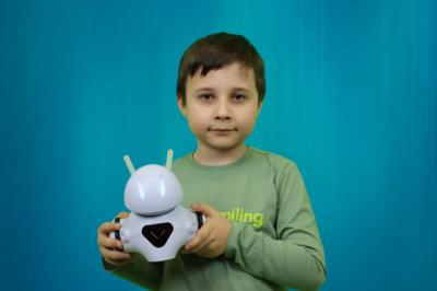 Uczestnik zajęć sztucznej inteligencji pozuje do zdjęcia z robotem Photon, którego trzyma w rękach.