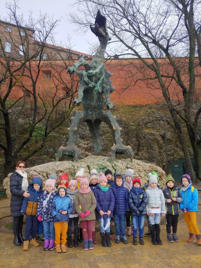 Dzieci pozuja do zdjęcia pod pomnikiem Smoka Wawelskiego.