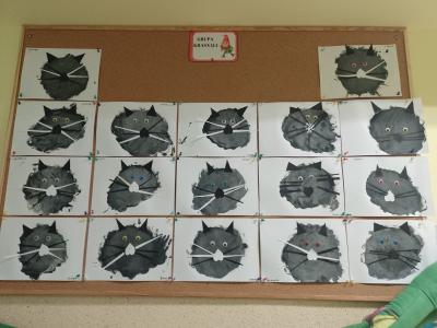 Zdjęcie przedstawia galerię wykonanych prac przedstawiających koty z grupy Krasnale. Na tablicy wiszą czarno – białe koty oraz widnieje napis Grupa Krasnale