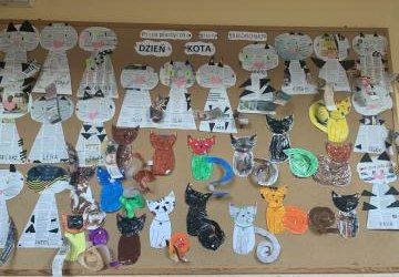 Na tablicy korkowej w szatni dzieci wiszą prace plastyczne - Koty wykonane z wyciętych gazet oraz papieru pokolorowane kredkami pastelowymi z długimi kręconymi ogonami.