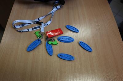 Na blacie stołu poukładane są niebieskie breloczki na klucze z imionami - całość wydrukowana na szkolnej drukarce 3D.
