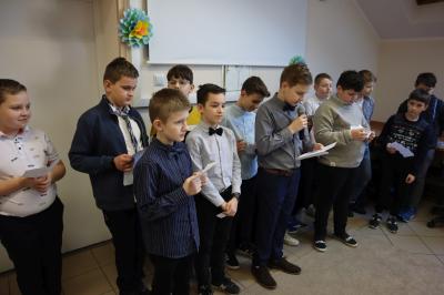 Odświętnie ubrani chłopcy z klasy Vb recytują wiersze oraz przekazują życzenia z okazji dnia kobiet.