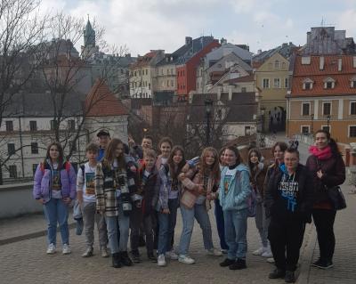 Uczniowie klasy 7a wraz z wychowawcą pozują do zdjęcia. W tle panorama Lublina.