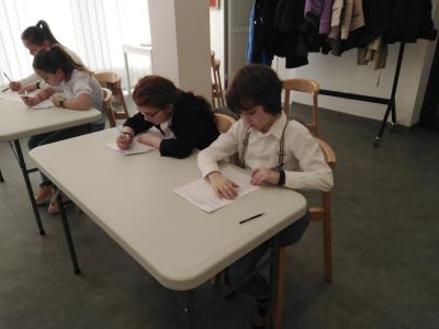 Uczestnicy konkursu siedzą przy stolikach i rozwiązują test