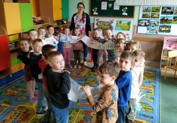 Dzieci trzymają długi arkusz papieru z rysunkami