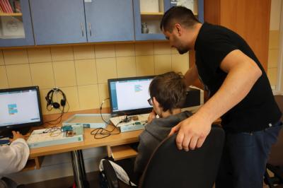 Uczniowie klasy VIb uczestniczą w zajęciach mechatroniki. Nauczyciel pomaga uczniowi