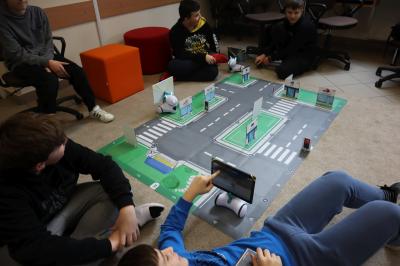 Uczniowie klasy VIb uczestniczą w zajęciach robotyki. Na dywanie rozłożone maty edukacyjna w raz z robotami.