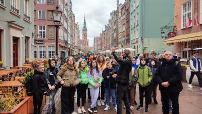 Dzieci uczestniczące w wycieczce zwiedzają  zabytkowe śródmieście Gdańska.