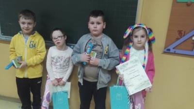 Wyróżnieni uczniowie pozują do zdjęcia wraz z nagrodami.