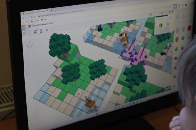 Uczniowie szkoły podstawowej biorący udział w warsztatach modelowania 3D na platformie Tinkercad. Ekran monitora na którym widac platformę projektowania Tinkercad.