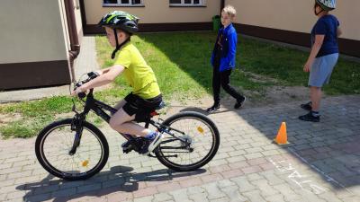 Egzamin praktyczny na kartę rowerową. Uczniowie pokonują rowerem plac manewrowy.