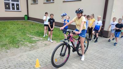 Egzamin praktyczny na kartę rowerową. Uczniowie pokonują rowerem plac manewrowy.