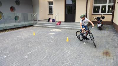 Egzamin praktyczny na kartę rowerową. Uczniowie pokonują rowerem plac manewrowy.