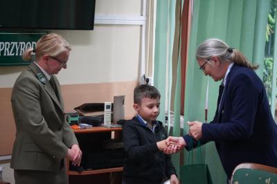 uczeń odbiera nagrodę i gratulację od komisji konkursowej