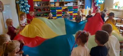 Dzieci trzymające kolorową hustę.
