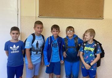 3.	Grupa chłopców z klasy 4b w niebieskich ubraniach stoi na szkolnym korytarzu.