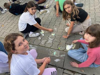 grupa dziewczynek rysuje kredą na kostce